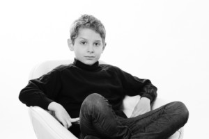 Kinderfoto in schwarz-weiß, Junge lässig im Stuhl sitztend